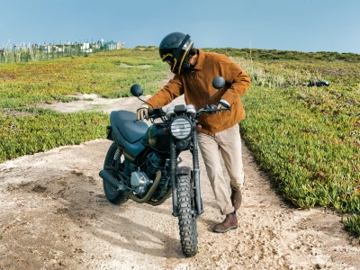 Een persoon die een motorfiets duwt.